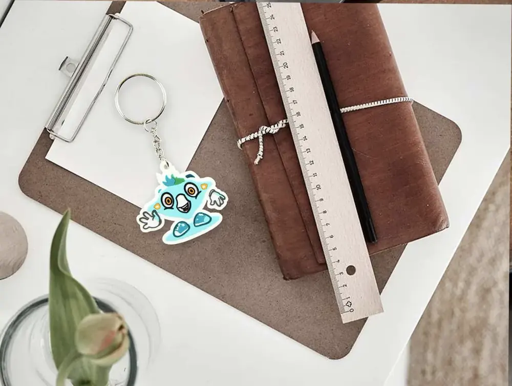 Portachiavi in PVC personalizzato a mascotte azzurra su una scrivania con righello e quaderno