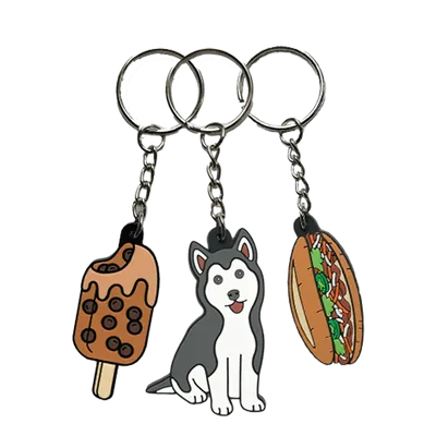 Tre portachiavi PVC affiancati: un gelato su stecco, un cane husky e un panino imbottito